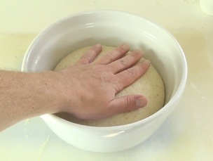 pressing the dough to release gas