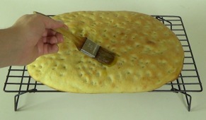 brushing the hot focaccia with olive oil